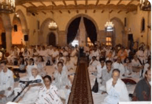 Gathering of people in a large hall listening to satsang